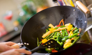 Chef cooking vegetables in wok pan